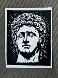 A black and white graphic art print depicting a classical bust of Agustus, shown flat on a textured gray surface.