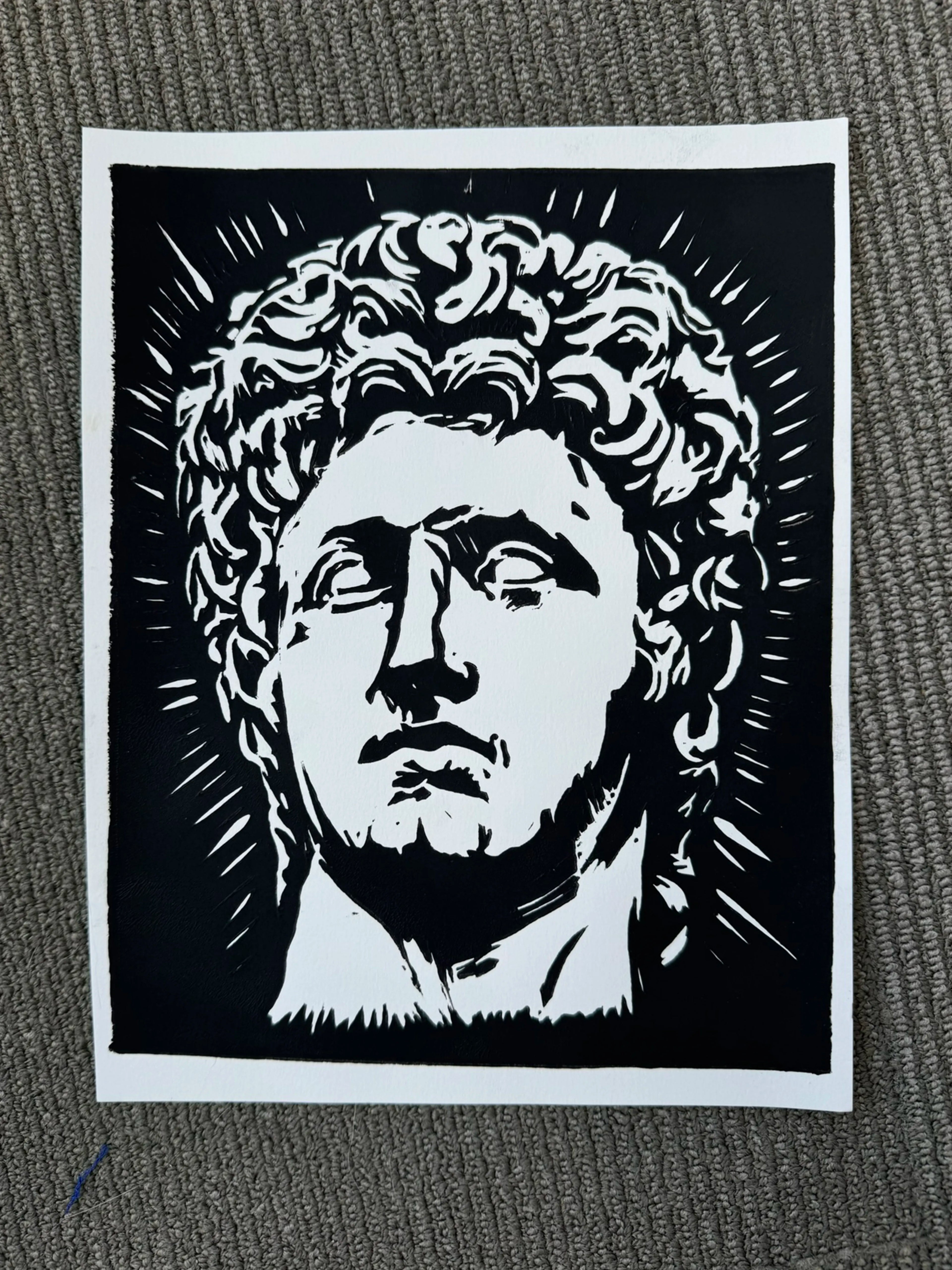 A black and white graphic art print depicting a classical bust of Agustus, shown flat on a textured gray surface.