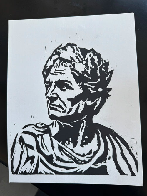 A black and white linocut or woodblock-style portrait print of an ancient Roman bust, shown on a white sheet of paper against a dark background.
